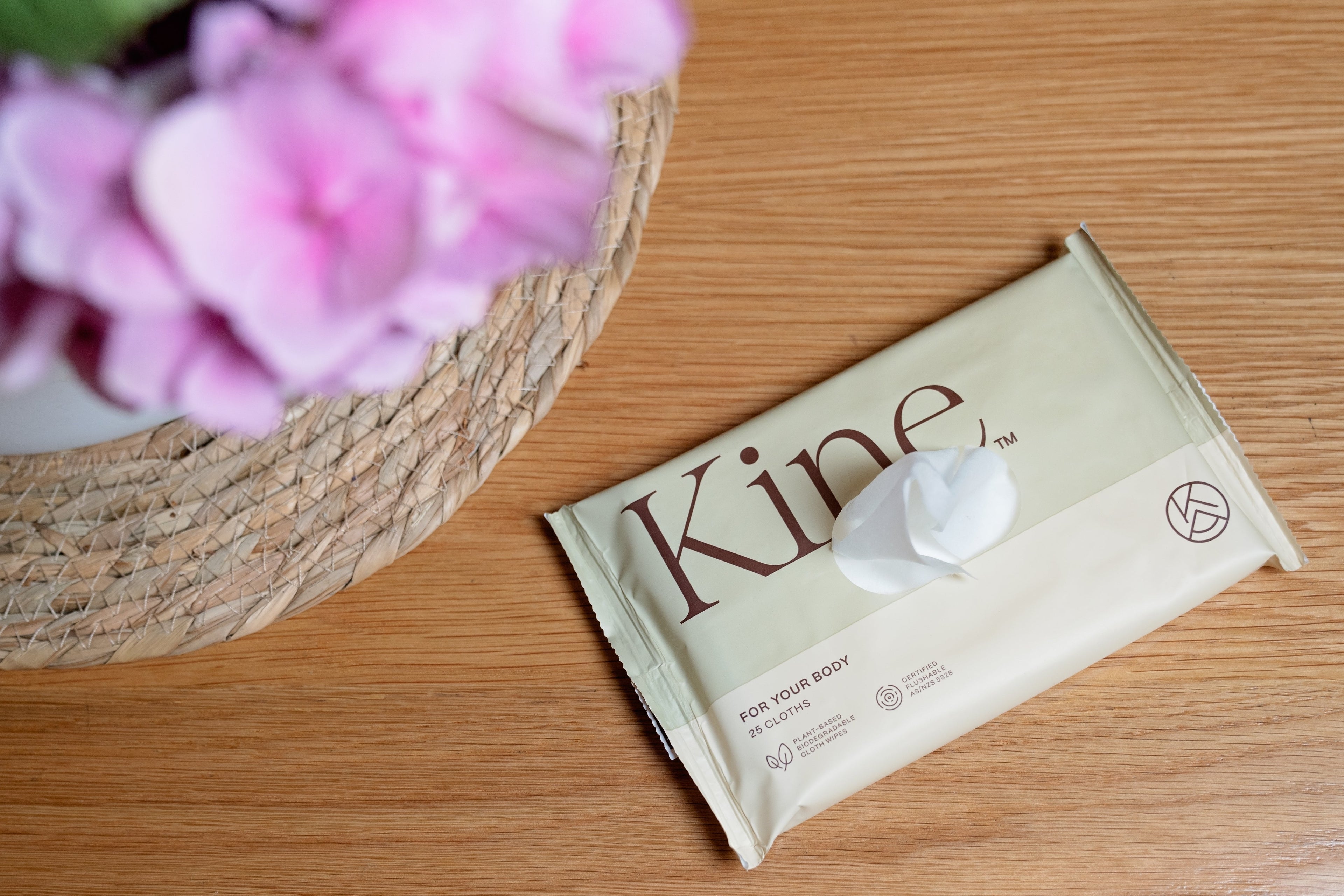 Kine tissue packet on a wooden surface with flowers in the background